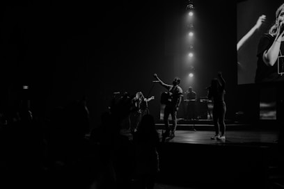 grayscale photo of men performing on stage