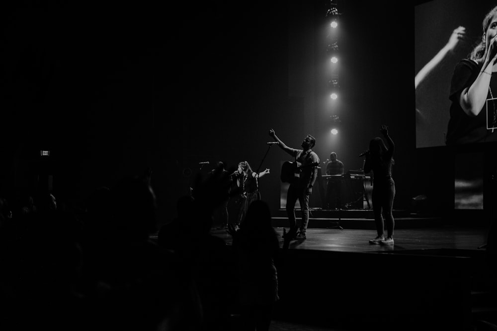 grayscale photo of men performing on stage