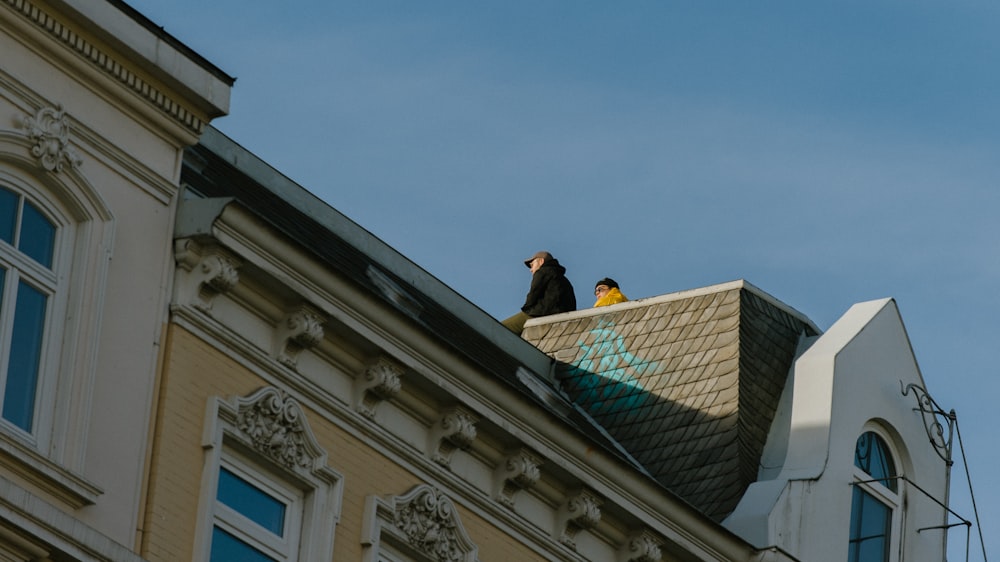 two person sitting on top of brown and white building