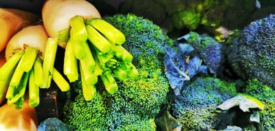 A close-up of fresh green broccoli heads and white radishes with their green stems, displaying a vibrant and healthy appearance.