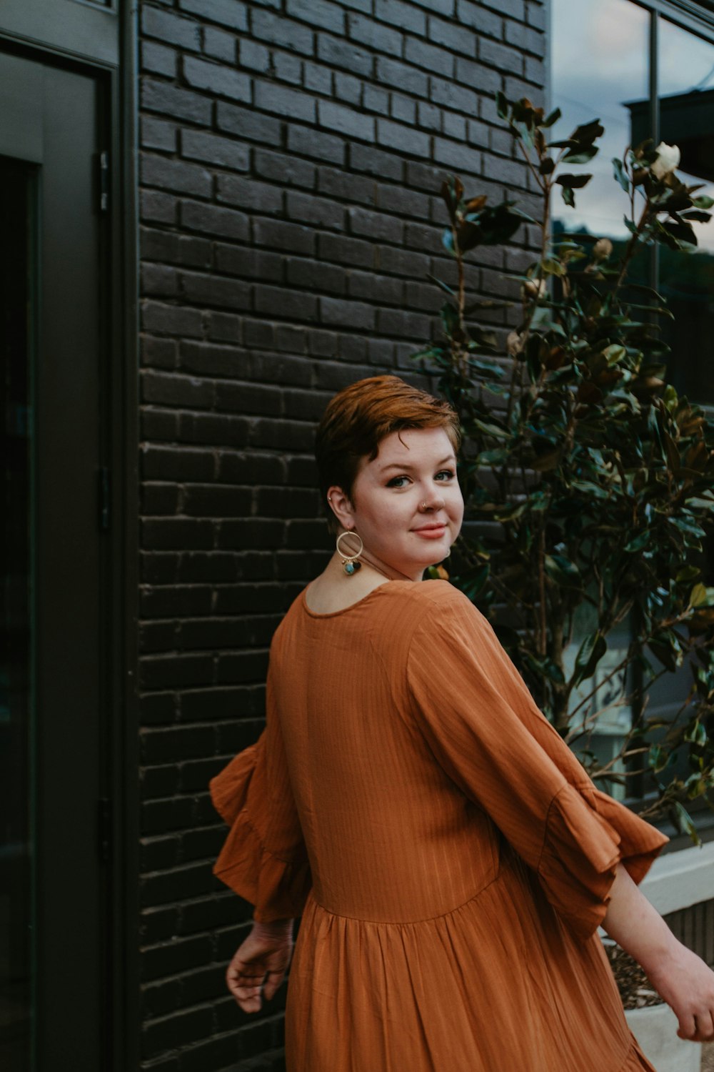 woman wearing trumpet-sleeved dress while standing beside brick wall