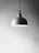 Close-up of a sleek, modern pendant resting on a soft fabric background.