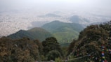 A panoramic shot of Gangtok city nestled among green hills under a clear blue sky.