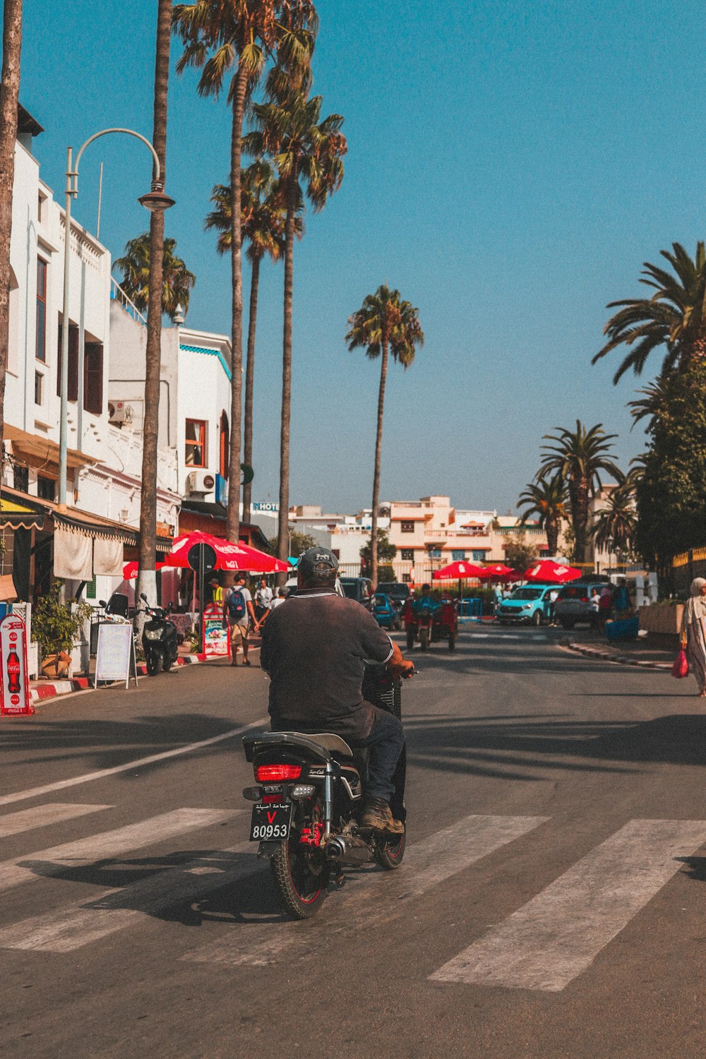 uomo in sella scooter vicino a persone che camminano accanto agli edifici durante il giorno