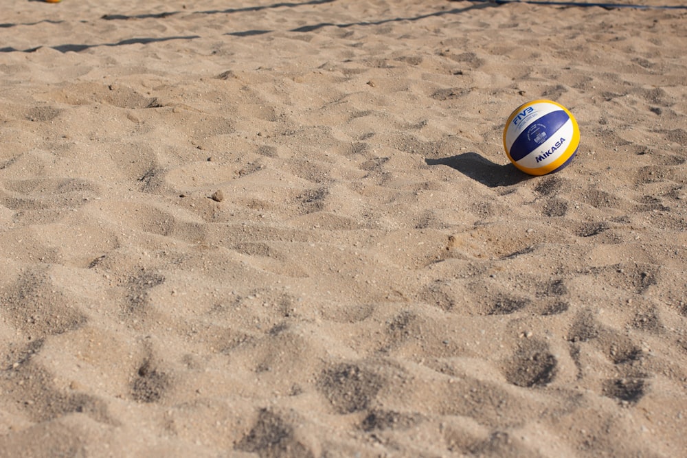 blue, yellow, and white volleyball on sand