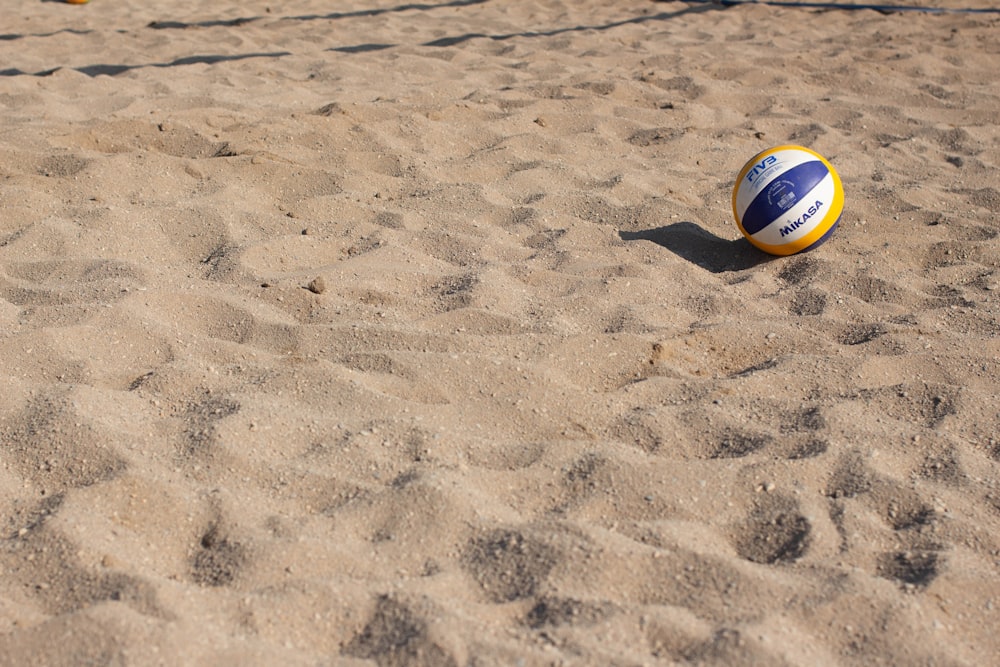 blauer, gelber und weißer Volleyball auf Sand