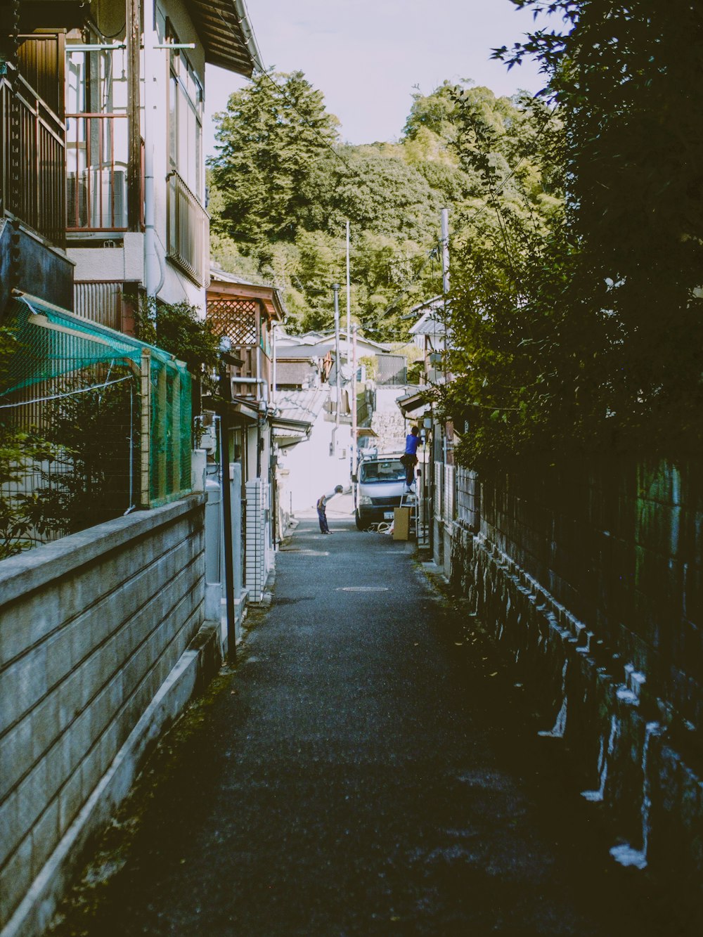 a narrow street with a fence and a building in the background