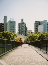 a couple of people riding bikes across a bridge