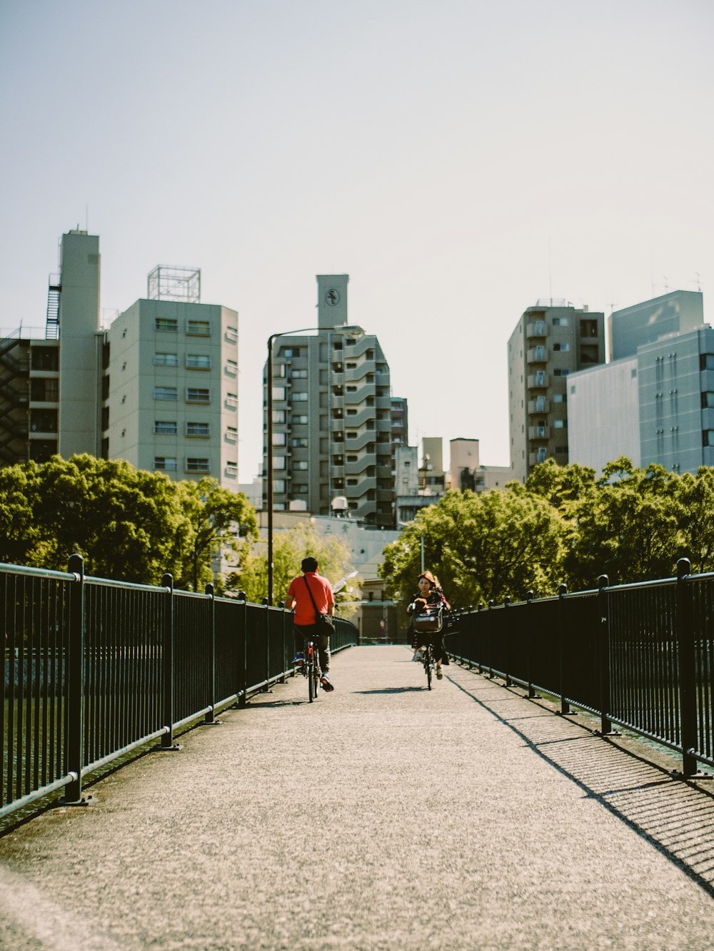 a couple of people riding bikes across a bridge