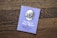 A book titled 'The Tale of Peter Rabbit' by Beatrix Potter is placed on a wooden surface. The cover is a light purple color featuring an illustration of a rabbit in a blue jacket. The text on the cover is positioned below the illustration.