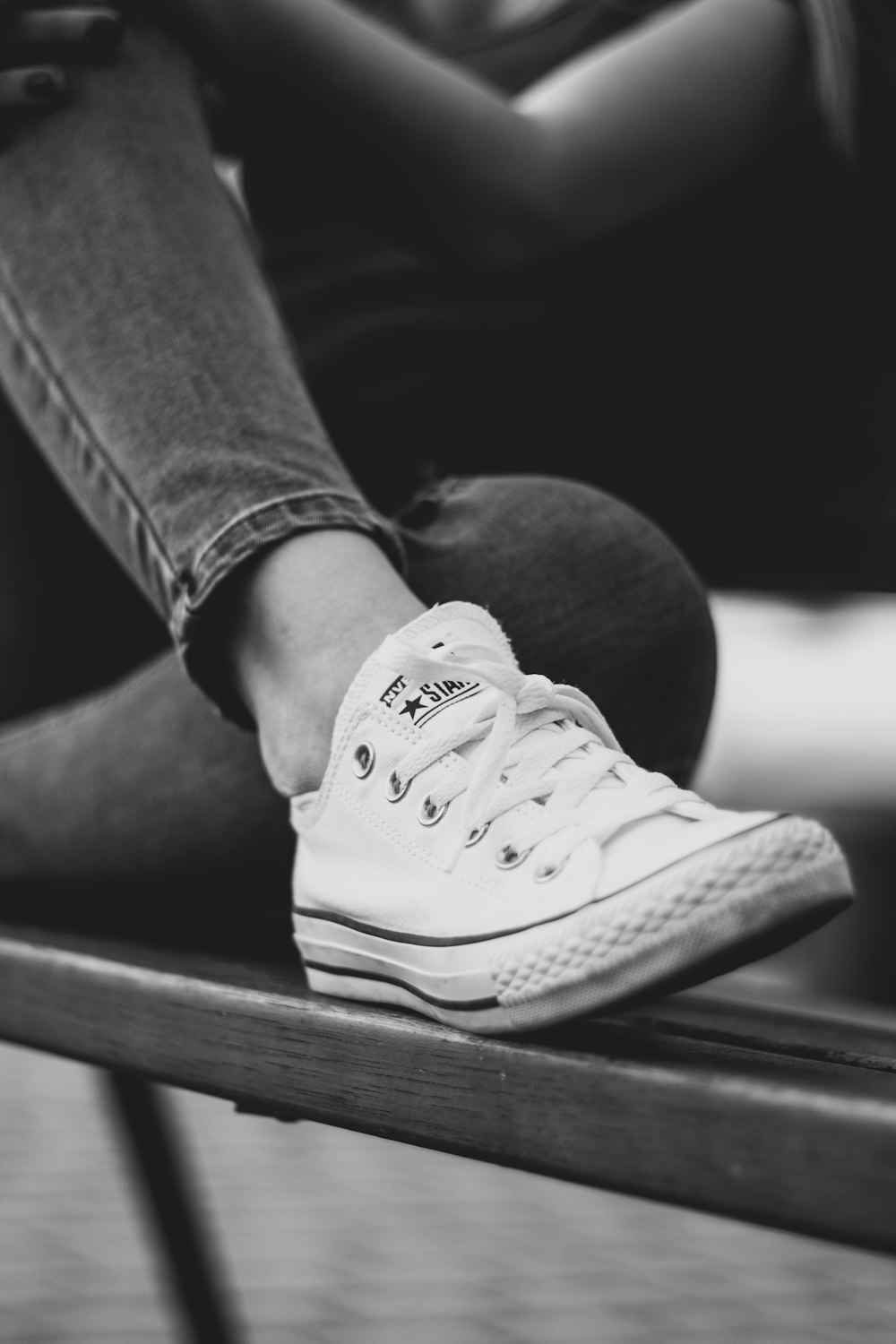 grayscale photo of person in jeans and sneakers