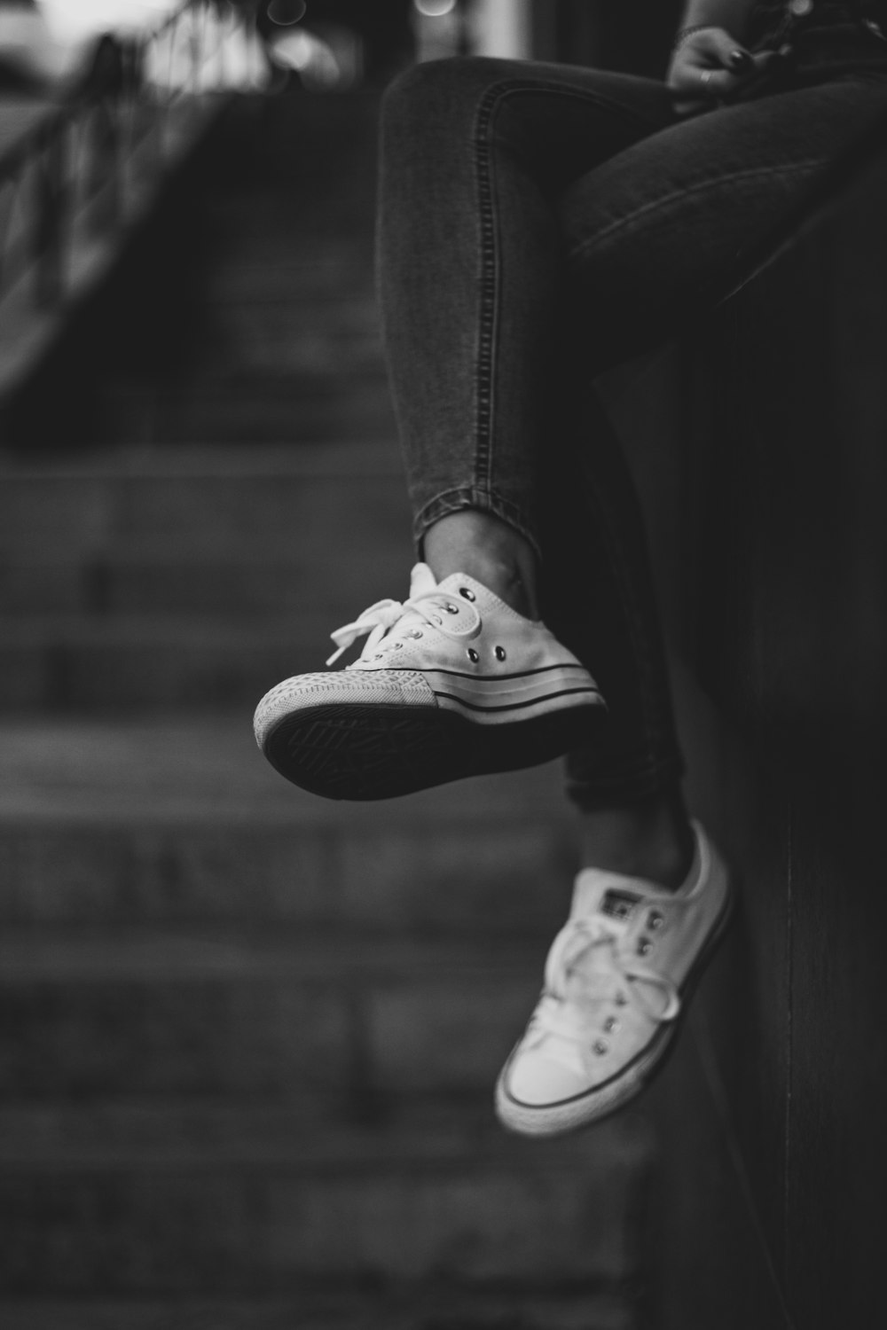 grayscale photography of person wearing jeans and sneakers