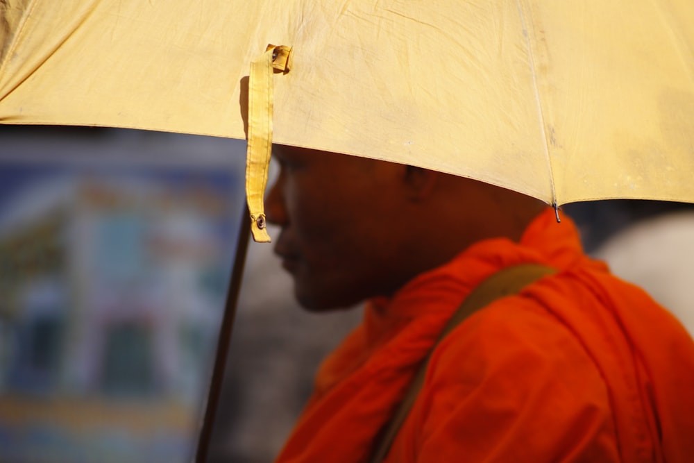 man wearing red top using white umbrella