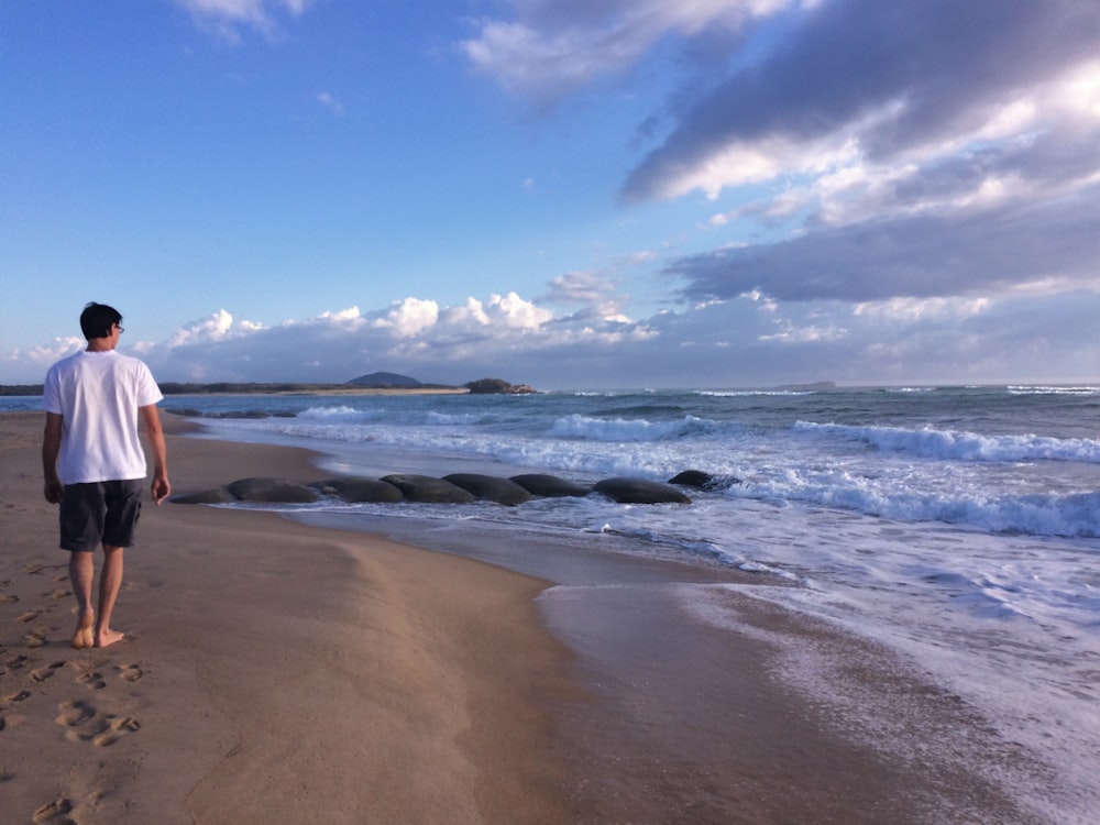 흰 셔츠를 입고 해변을 걷는 남자
