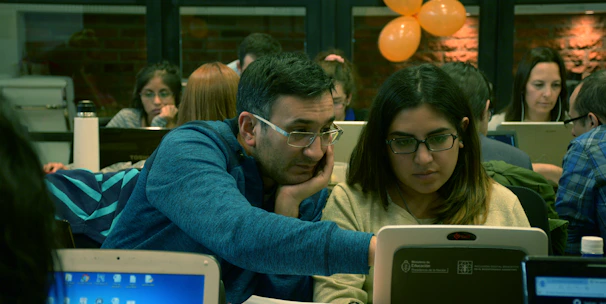A team collaborating around a laptop with DevOps tools and AWS dashboards displayed on the screen.