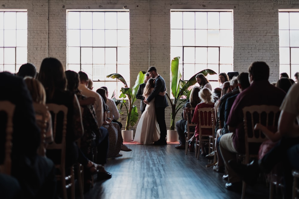 wedding couple hugging near people sitting inside building