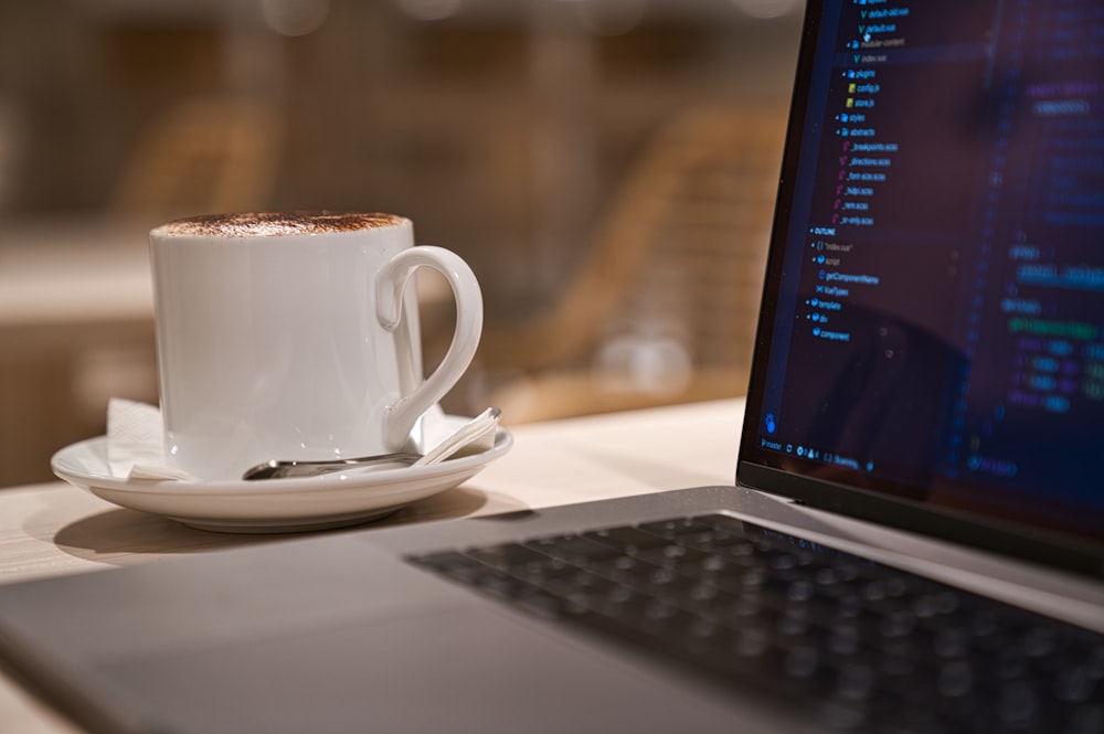 black laptop computer beside white ceramic mug close-up photography