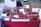 The table is covered with a variety of colorful, hand-crafted coin purses and eyeglass cases displayed in baskets and trays. Each item features vibrant designs with animal faces, patterns, and motifs. Some signage is visible with text in Japanese, providing prices and product details.