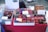 The table is covered with a variety of colorful, hand-crafted coin purses and eyeglass cases displayed in baskets and trays. Each item features vibrant designs with animal faces, patterns, and motifs. Some signage is visible with text in Japanese, providing prices and product details.