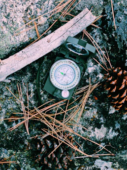 Close-up of a rugged map and compass on a wooden table with charcoal black and cream tones.