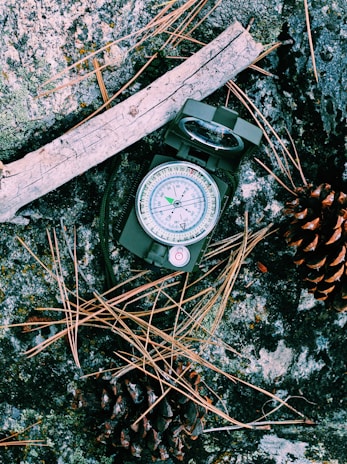 A detailed shot of a GPS device and compass resting on a map on a wooden table.