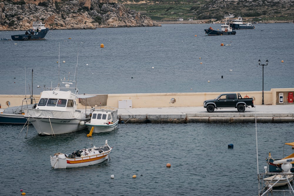 white yachts on body of water and black pickup truck on road during daytime