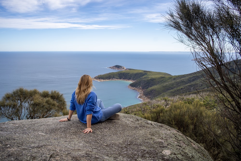 person sitting on gray rock during daytime