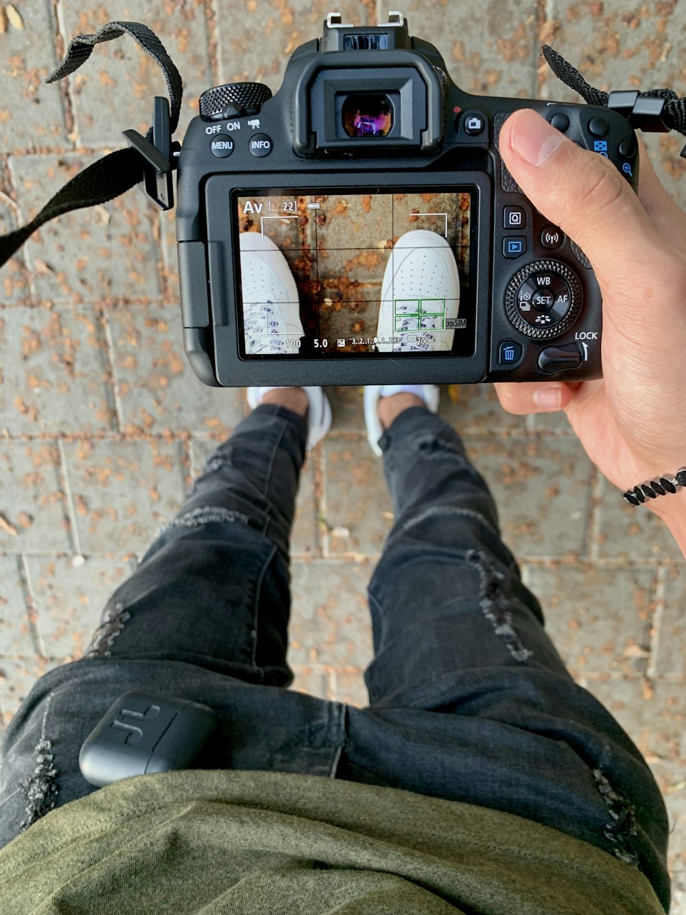 person using DSLR camera and taking photo of white sneakers