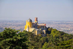 gray and yellow castle at the top of a hill