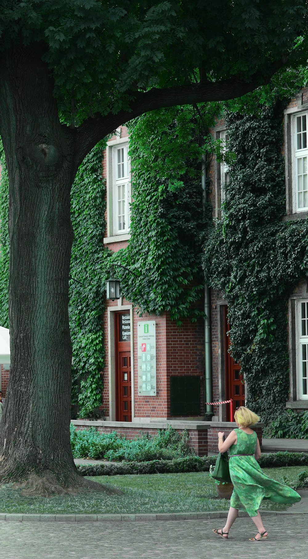 woman in green sleeveless dress walking under tre