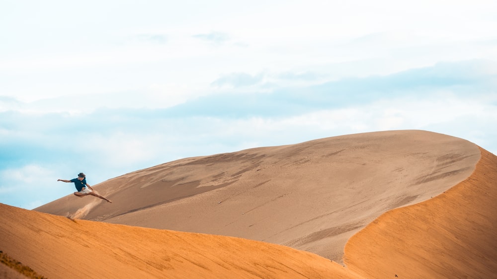 man jumping in desert at daytime