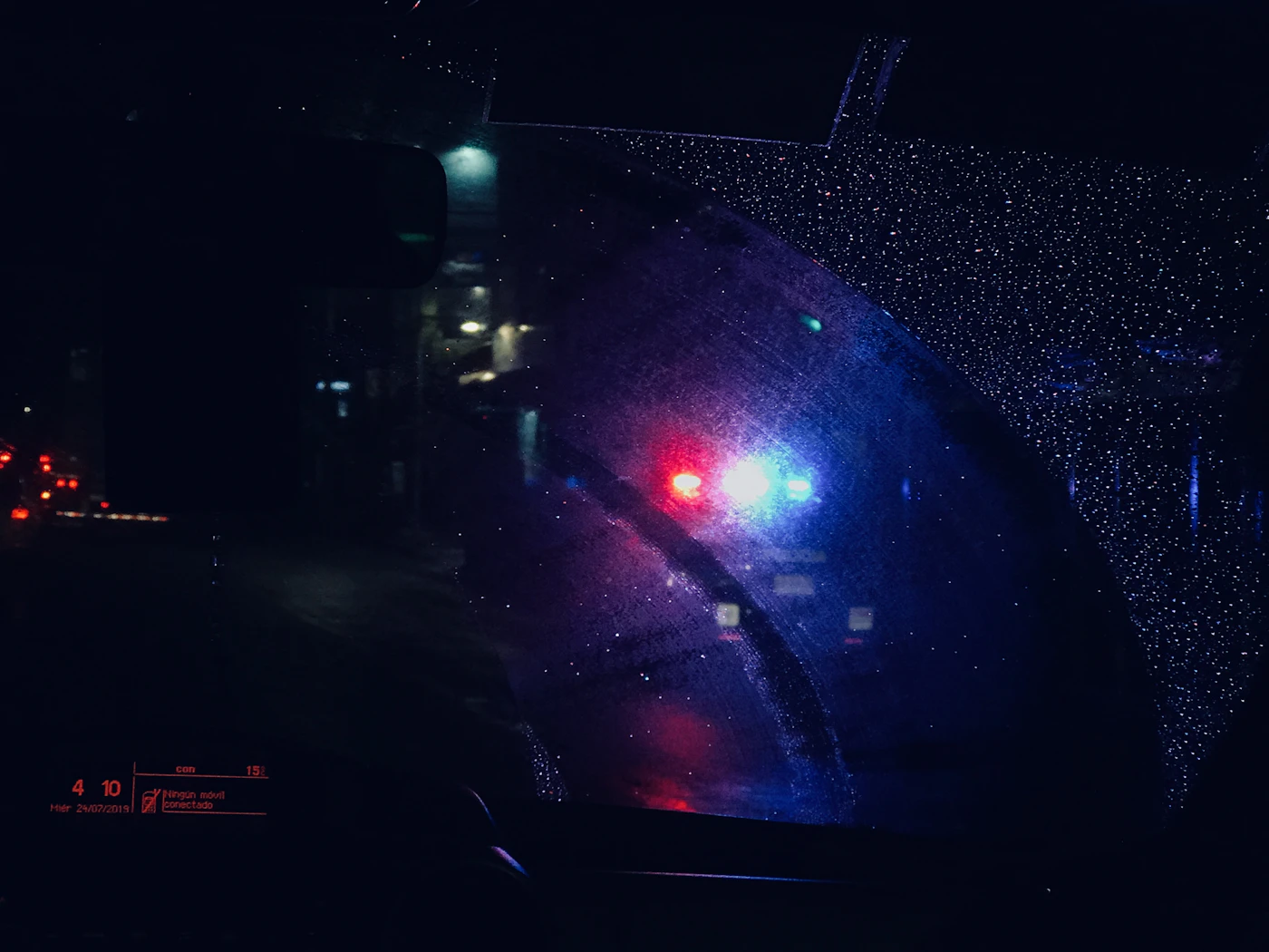 The view through a car's rear-view mirror on a dark road at night.