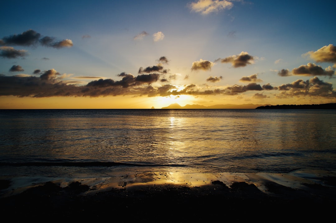 calm sea under clear blue sky, Au loin le rocher du Diamant soleil couchant.<p></figure>Prise de vue depuis la Grande Anse des Salines à Ste-Anne.