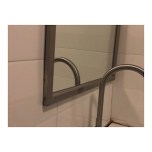 A close-up of a beautifully framed mirror on a bathroom wall.