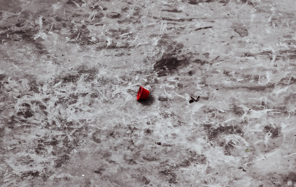 a red umbrella sitting on top of a dirty floor