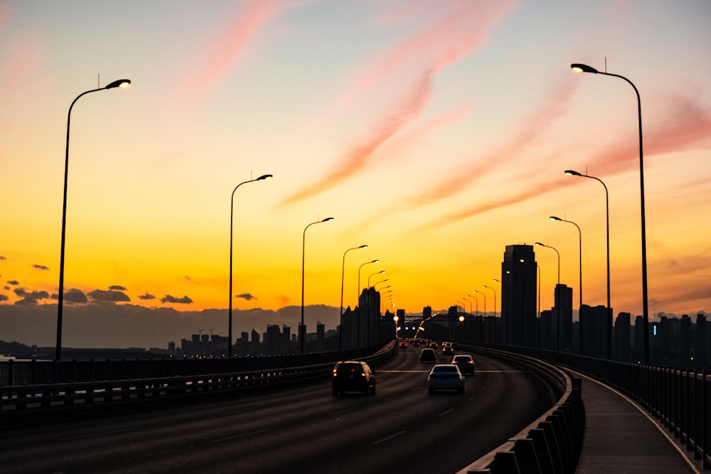 a sunset view of a highway with cars driving on it