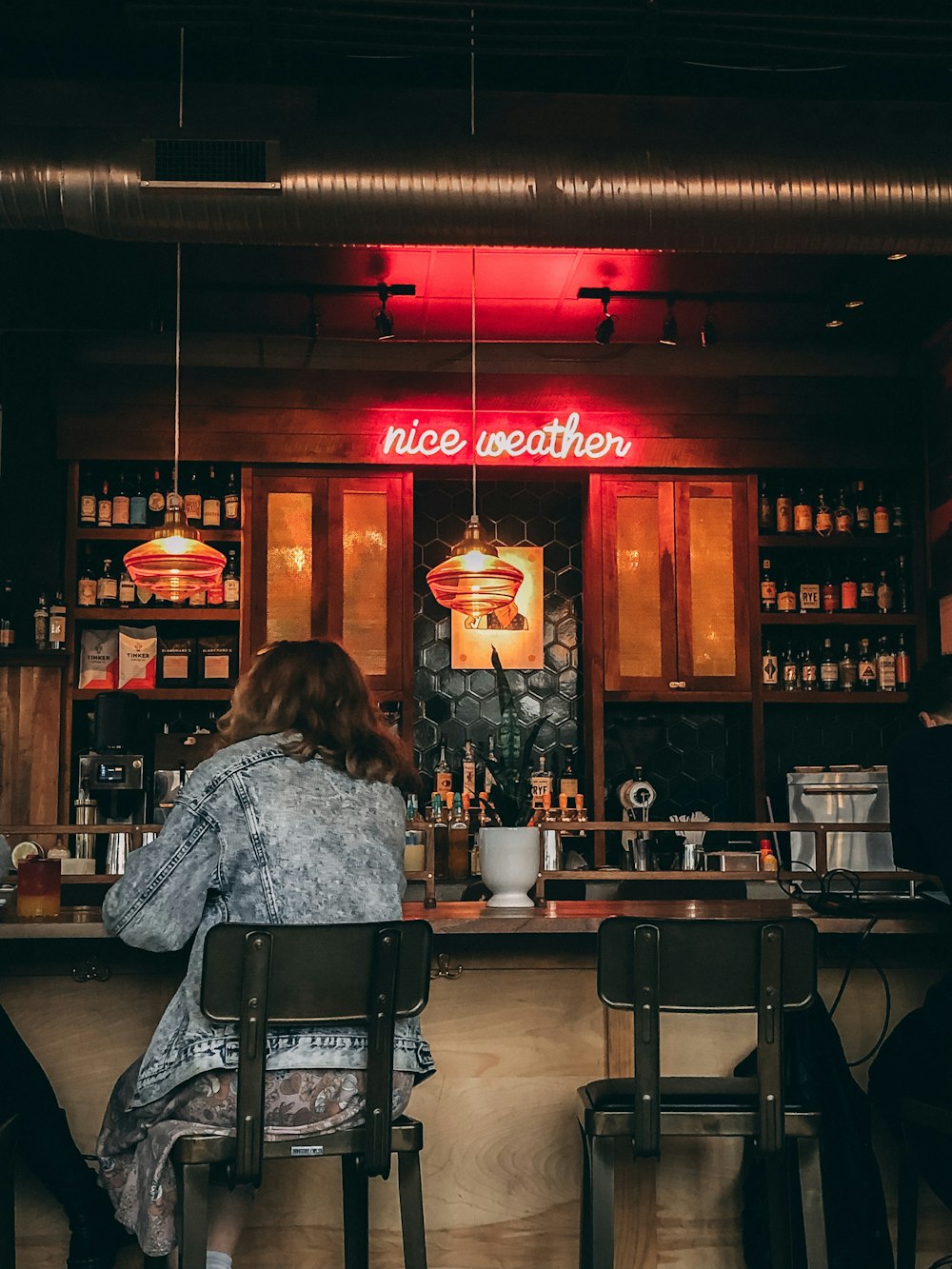 woman wearing blue denim jacket sitting on bar stool