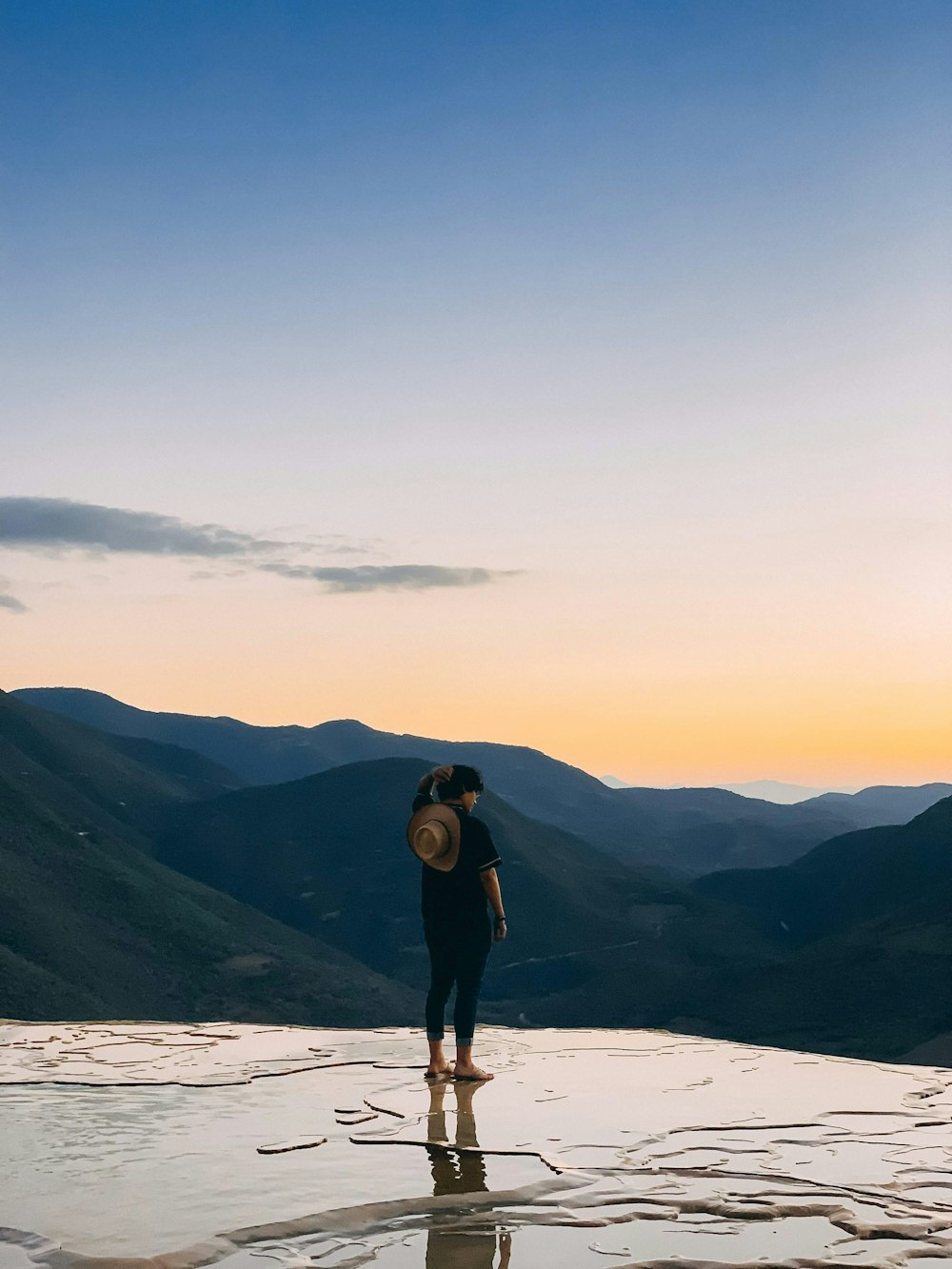 person standing on wet pathway facing mountain during daytime