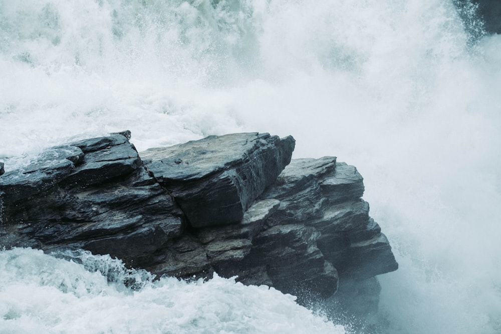 a man standing on top of a rock next to a waterfall