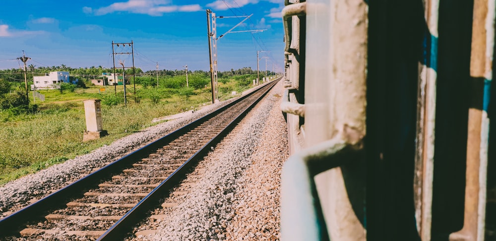 a train traveling down train tracks next to a lush green field