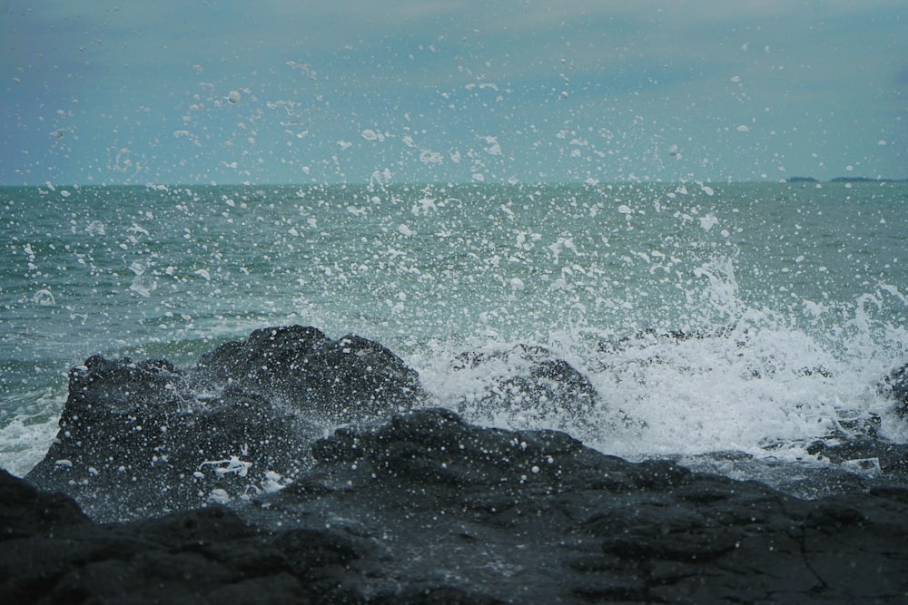 black rock formation beside body of water close-up photography