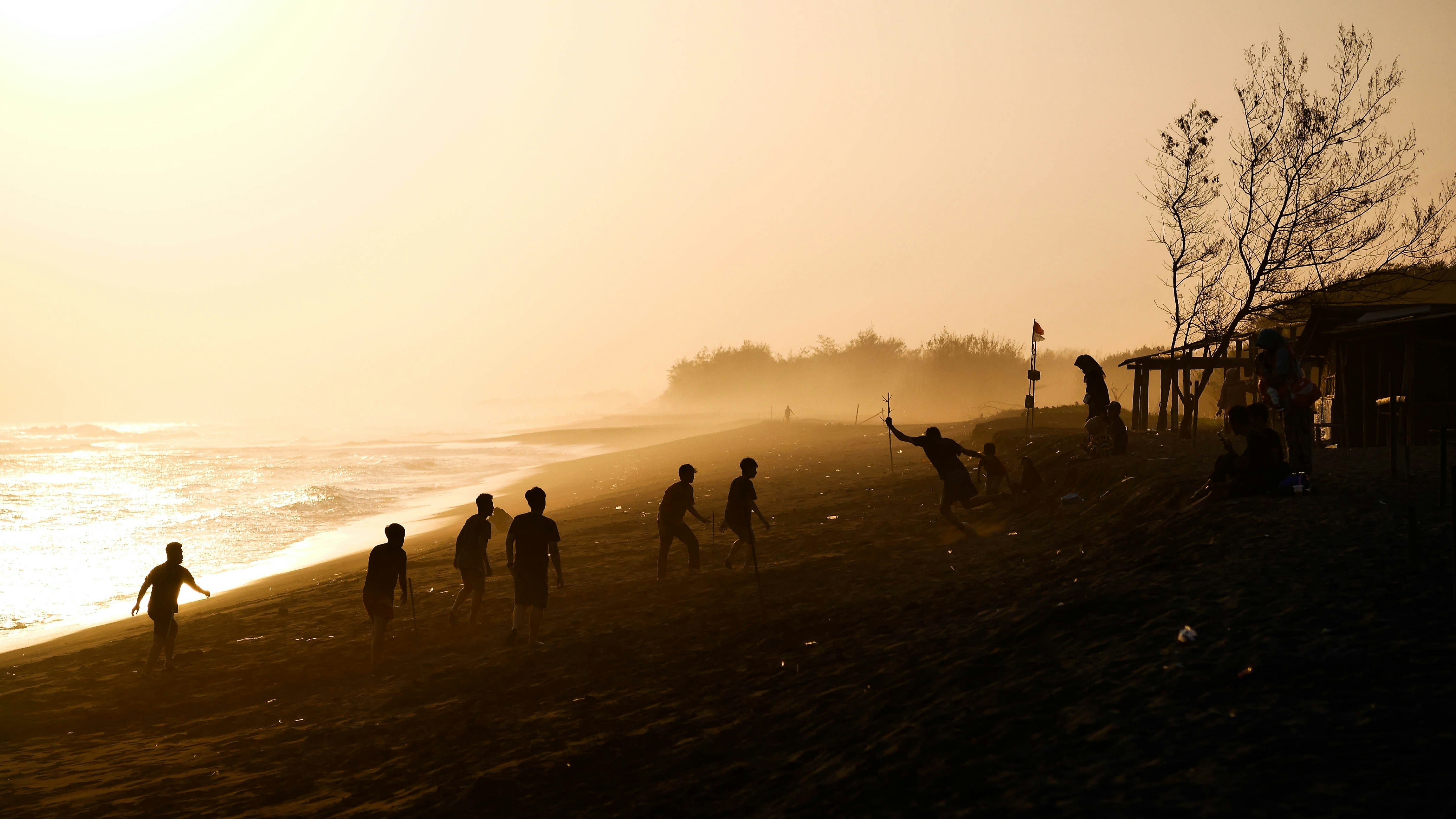Uomini che giocano in riva al mare durante l'ora d'oro