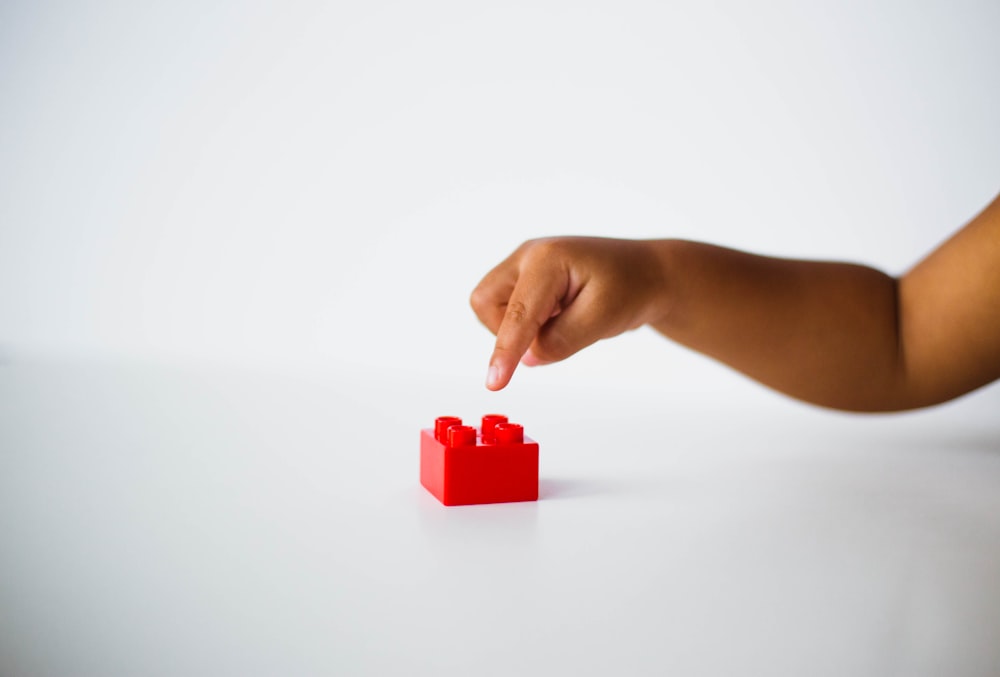 child pointing to red interlocking brick toy