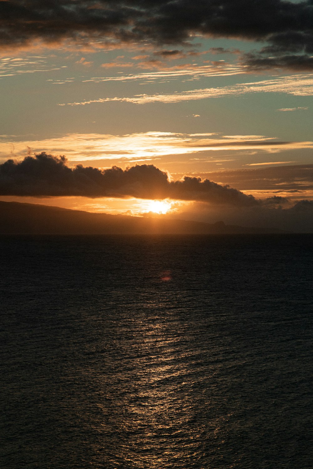 a large body of water with a sunset in the background