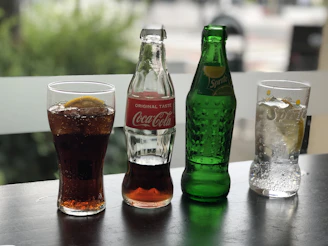 Refreshing soda cans and colorful fruit juices on a wooden table with ice cubes.
