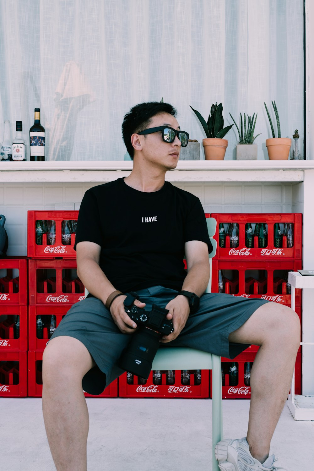 man in black t-shirt and sunglasses holding DSLR camera