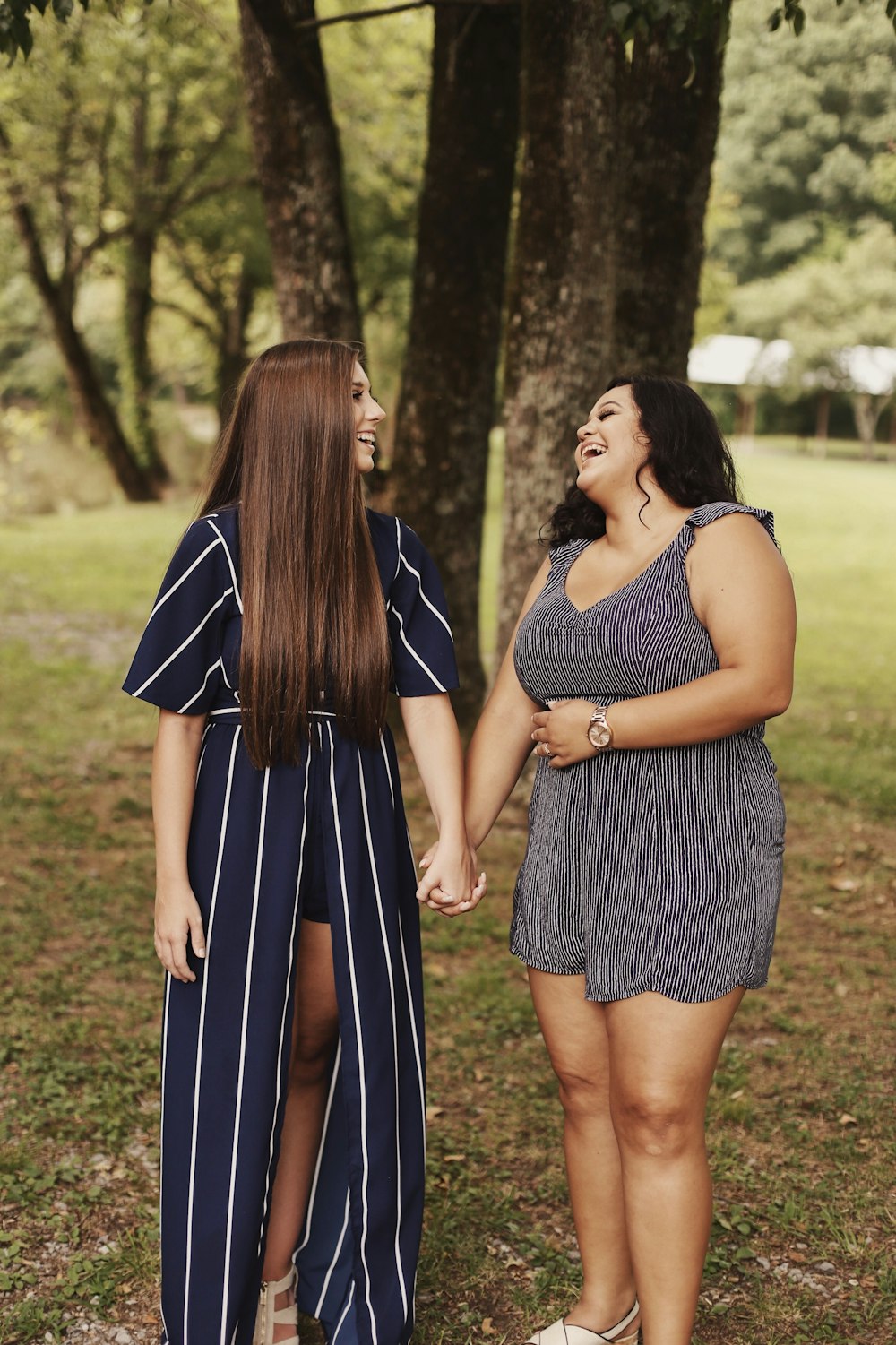 two women laughing standing near tree