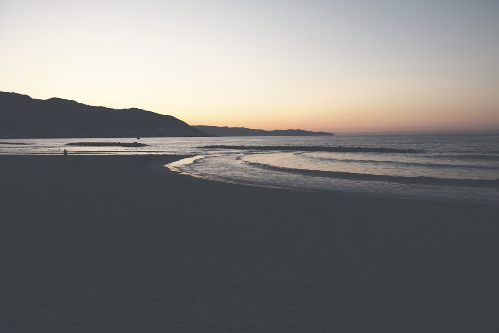 body of water near mountain at golden hour