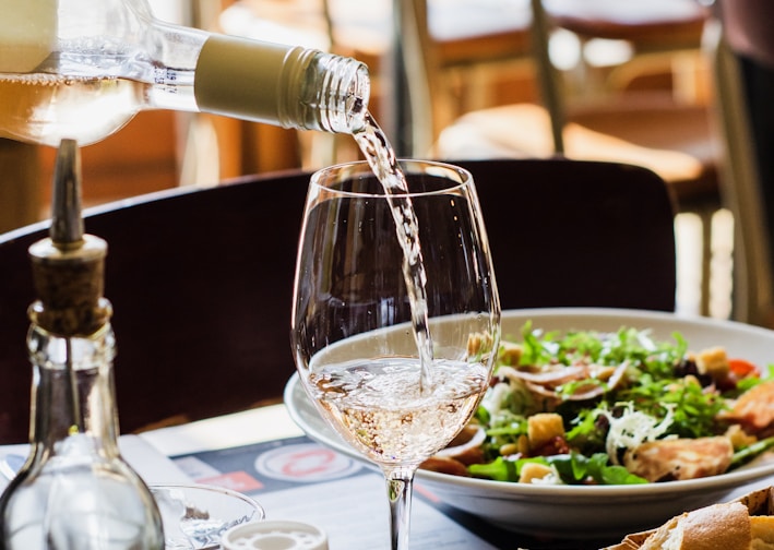 person pouring wine in wine glass