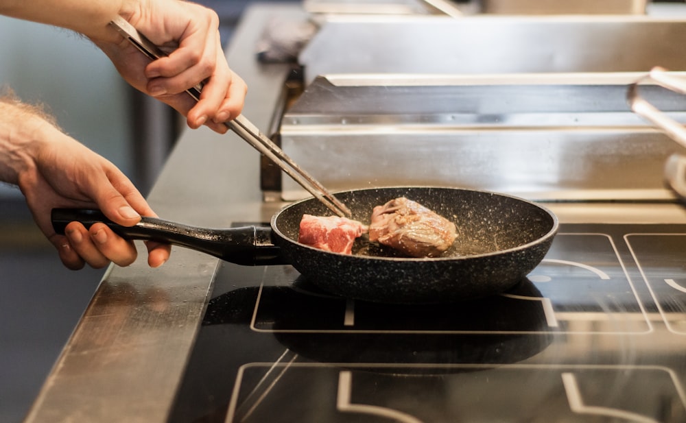 Unbekannte Person brät Fleisch